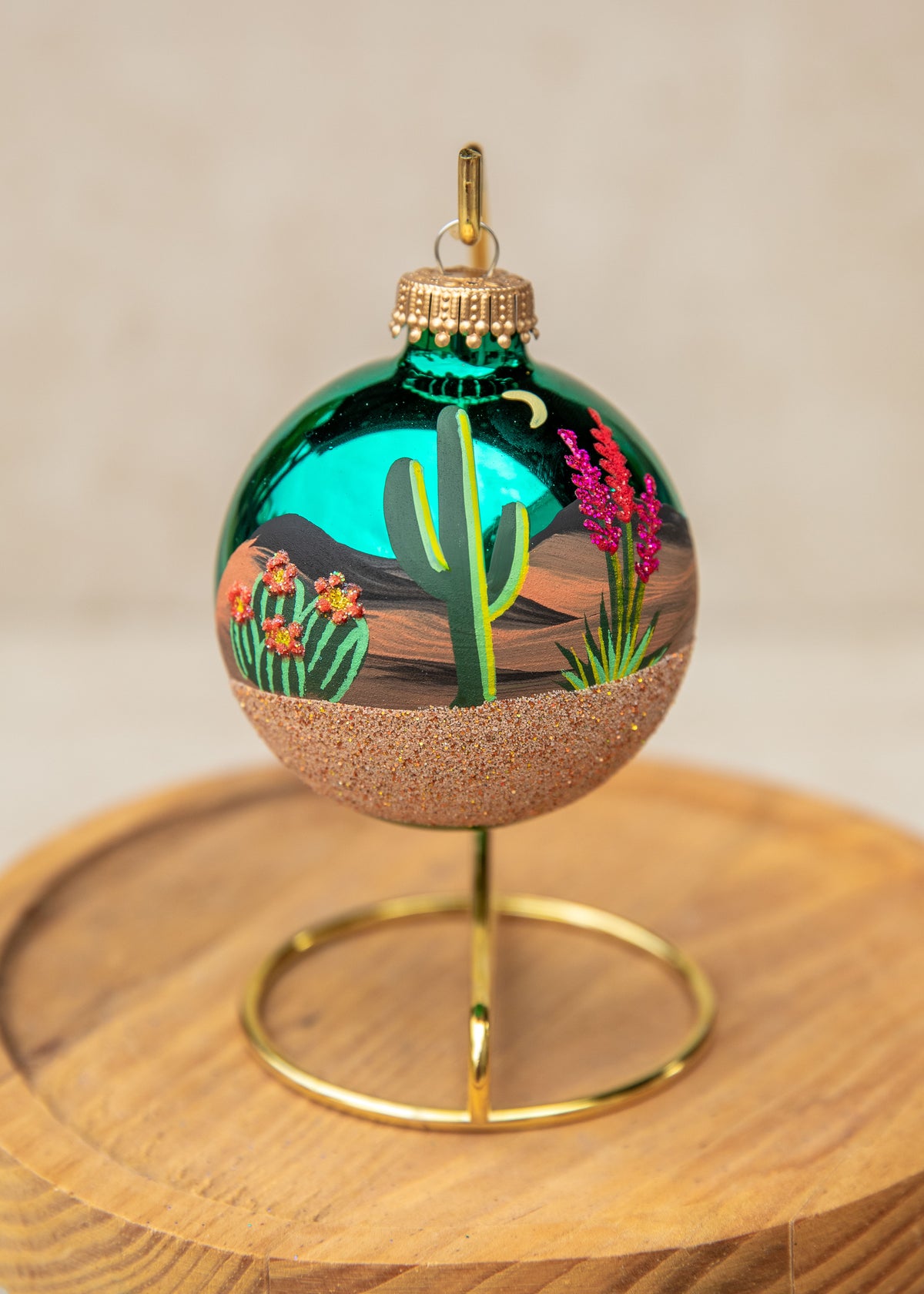 Desert Moonlight Hand Painted glass ornament by Brenda, a saguaro and blooming cactus under a crescent moon on a teal ornament