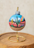 After the Storm Hand Painted glass ornament by Brenda, a saguaro in the center with a soft rainbow on the right