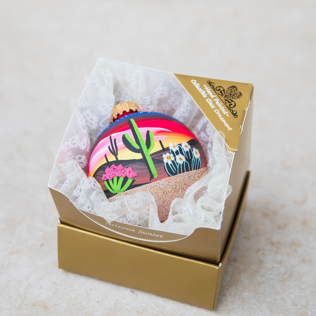Hand Painted ornament nestled in a ruffle inside the open two-piece gold gift box, with a title card in front