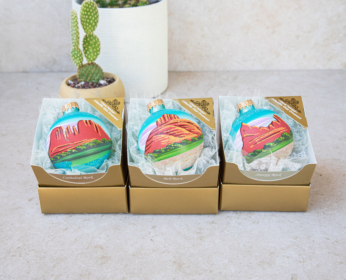 The three Sedona Hand Painted ornaments, Bell Rock, Snoopy Rock, and Cathedral Rock, side by side in gold gift boxes