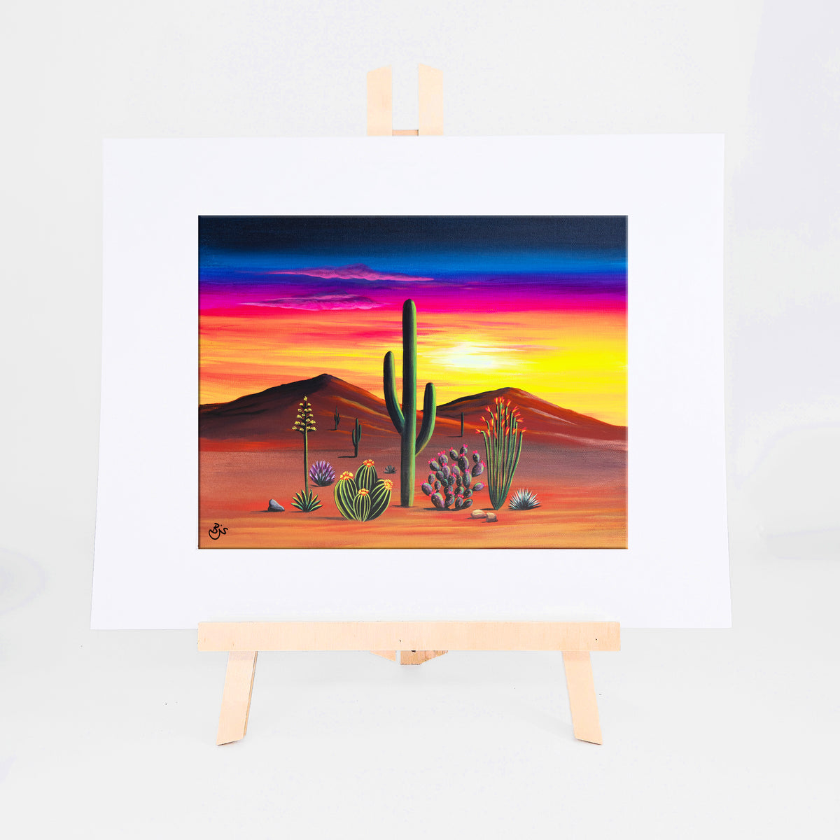 Sunset in Bloom, Brenda's painting of a glowing sunset behind tall saguaros and colorful desert blooms, shown as a matted 8x10 art print