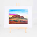 Arizona Sunrise, Brenda's painting of desert peaks, saguaros, and wildflowers under a colorful morning sky, shown as a matted 8x10 art print