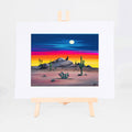 Howlin' Coyote, Brenda's painting of a coyote howling from a rocky ridge under a full moon and sunset sky, shown as a matted 8x10 art print